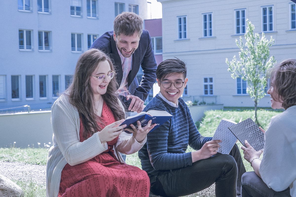 Menschen sitzen im Freien und lesen in der Bibel