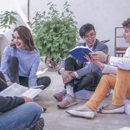 Menschen sitzen am Boden beisammen und lesen in der Bibel